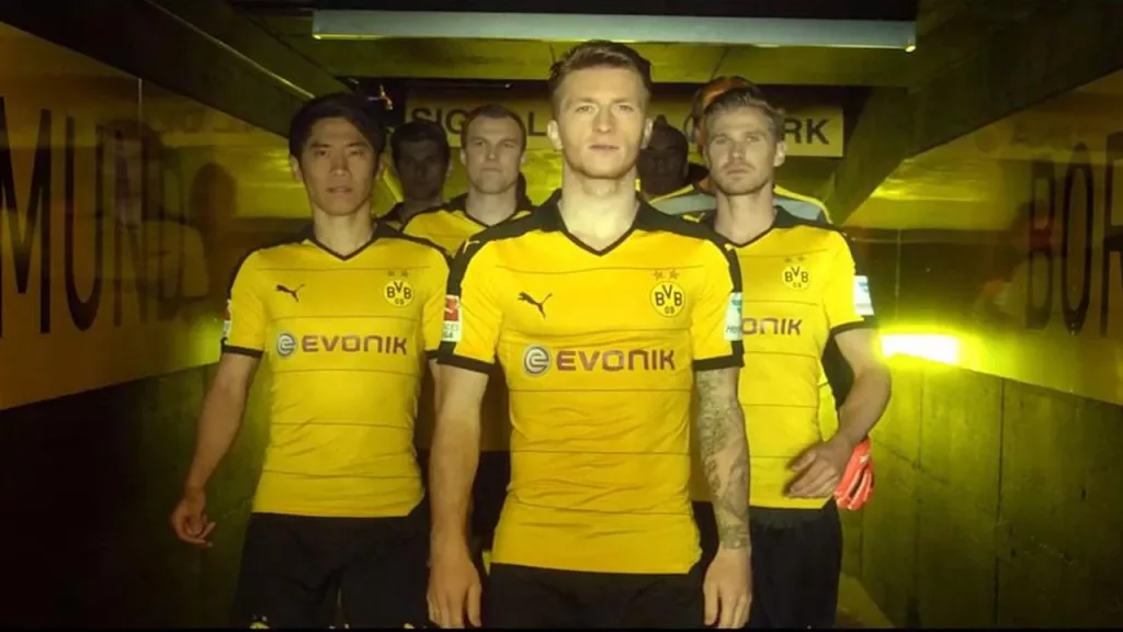 BVB Fussball Mannschaft läuft in gelbem Puma Trikot der Kamera entgegen.